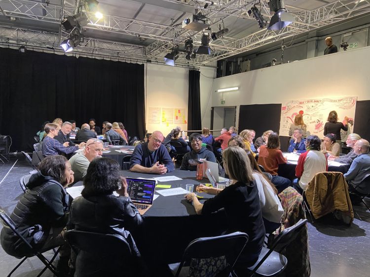 people sitting at round tables and talking and making notes